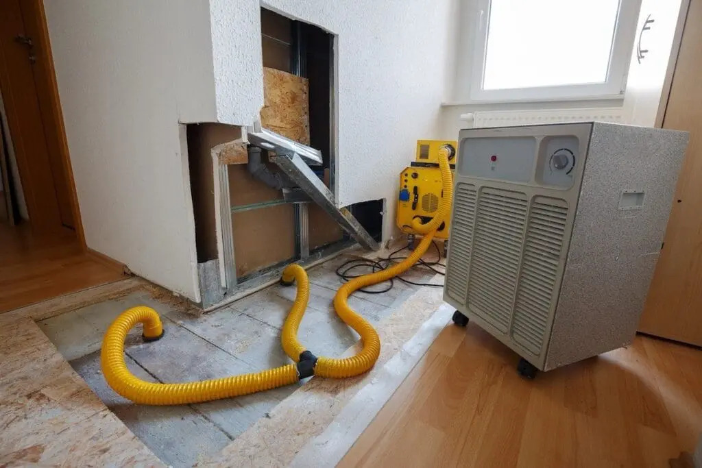 Air movers and dehumidifiers positioned throughout a water-damaged room during structural drying