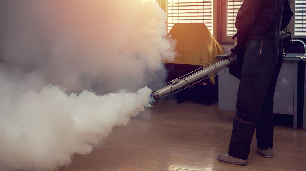 technician using a thermal fogger to neutralize smoke odors in a residential hallway