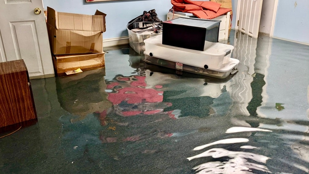Flooded living room with standing water and damaged flooring