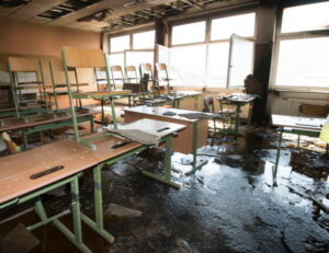 Fire damage restoration professional assessing smoke and soot damage inside a Covington LA private school classroom requiring specialized educational facility restoration and compliance response