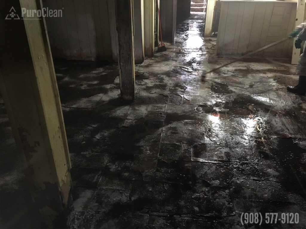 Water-damaged interior with wet floors and exposed beams, indicating a need for restoration.
