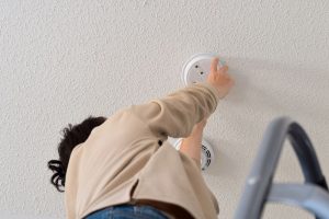 A woman conducts smoke alarm maintenance in her Greer home.