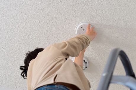 A woman conducts smoke alarm maintenance in her Greer home.
