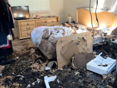 Severe residential fire damage in a bedroom, including soot, debris, and destruction from smoke and heat.