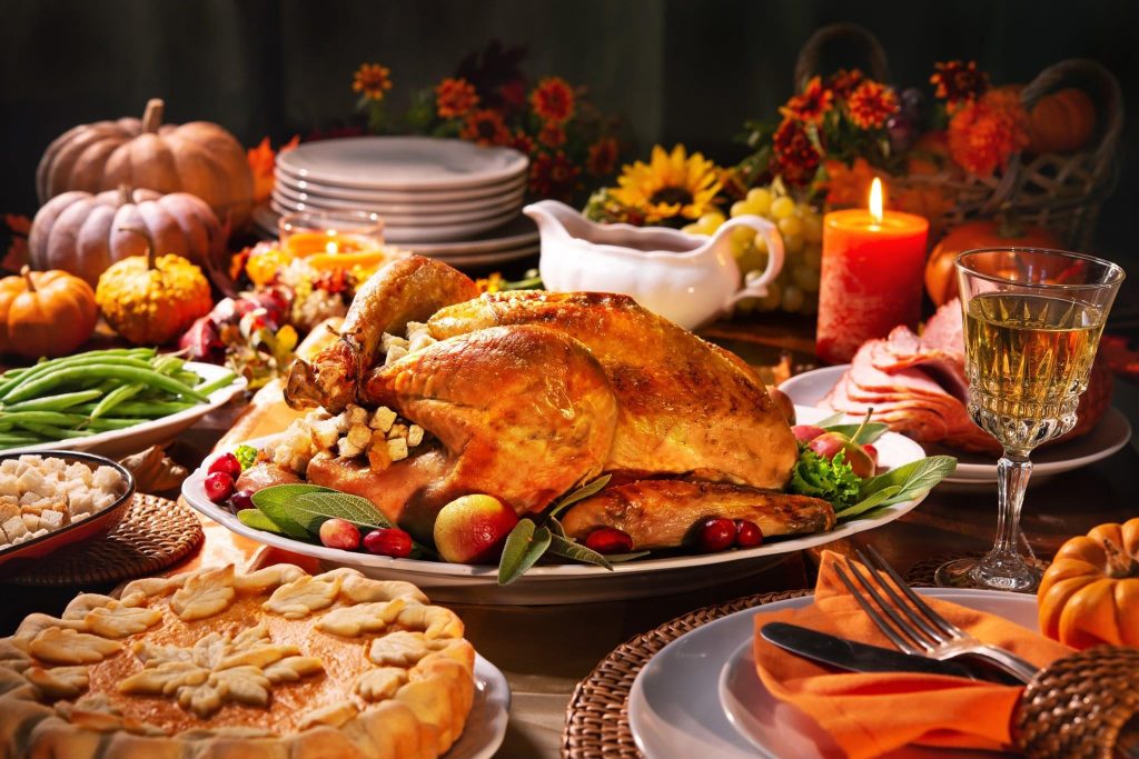 A beautifully arranged Thanksgiving dinner featuring a roasted turkey, side dishes, pie, and autumn decorations.