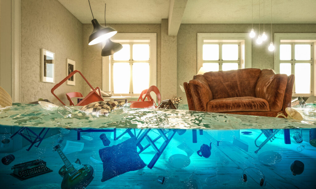 A modern room is dramatically flooded, showing furniture above water and various household items submerged below