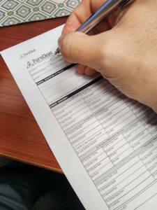 A hand uses a pen to complete a PuroClean property damage assessment document.