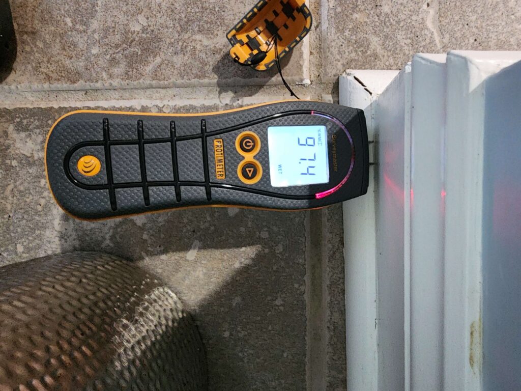 A Protimeter Surveymaster displays "97.4 WET" with a red