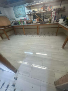 A hobby workshop features shelves of model airplanes, a long workbench, and newly installed light gray floor