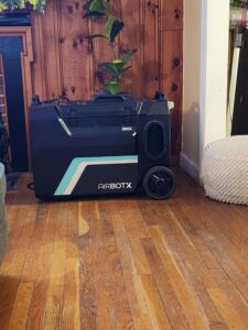 A black portable AIRBOTX 390X air purifier with wheels sits on a