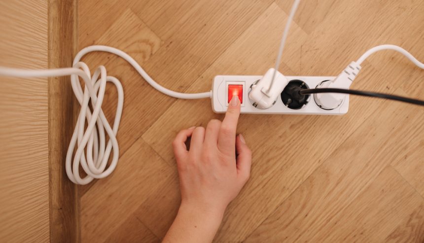 Top view of female hand turn on the extension cord at home.
