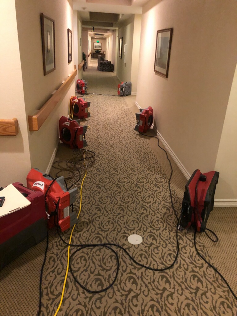 air movers set up in hallway of retirement home after water damage from broken water supply line.