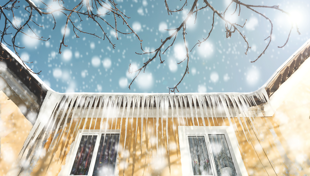Icicles hang from a roof with snow falling in the background, highlighting winter weather conditions.