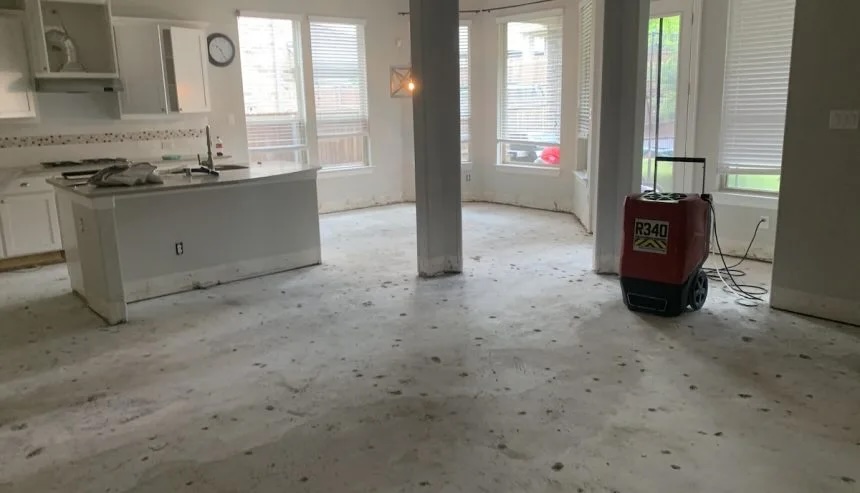 An unfinished room with a bare concrete floor, kitchen island, and a red industrial dehumidifier