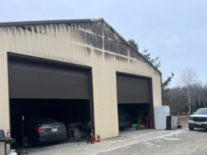 Structural fire damage on a commercial garage in Green Bay, with visible soot stains above the large overhead doors.
