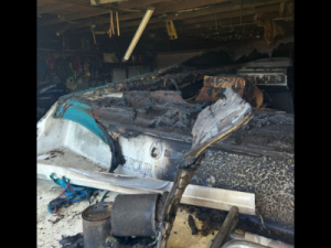 Fire-damaged garage with extensive smoke and burn damage to a boat, highlighting the importance of fire resilience and expert reconstruction in Green Bay.
