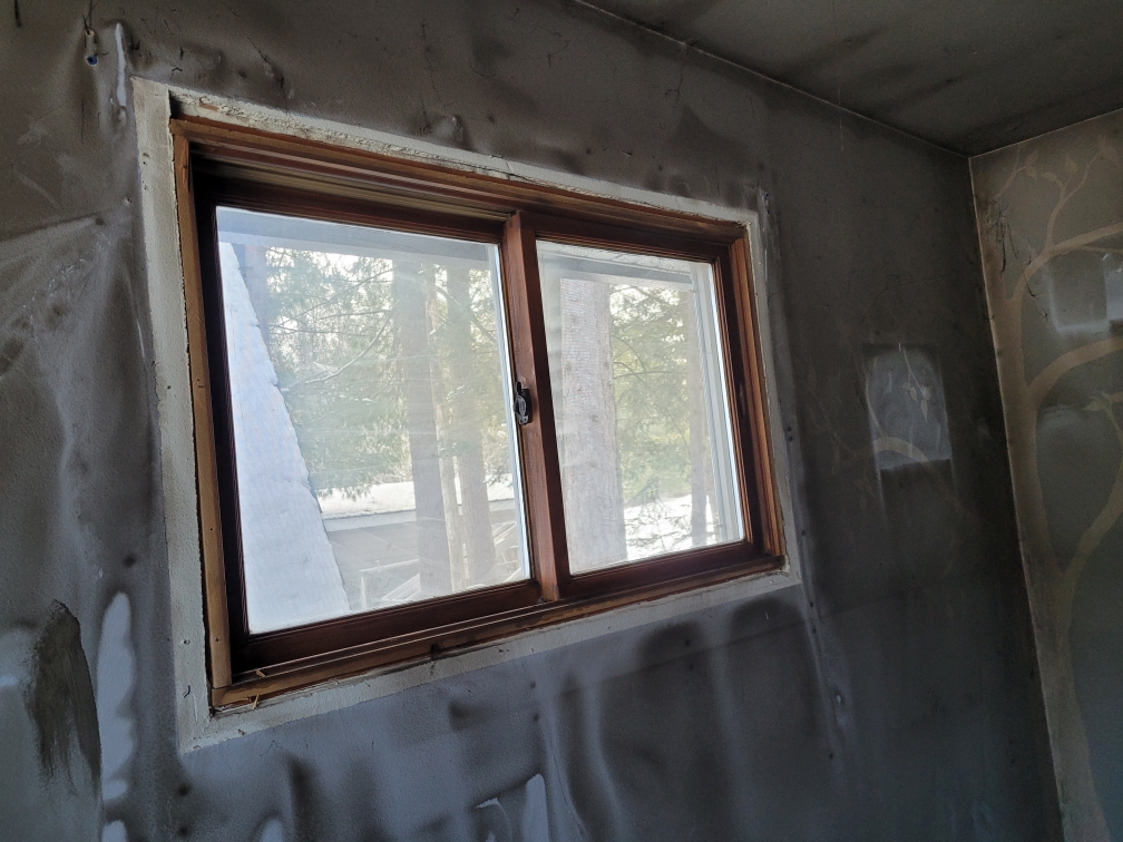 Heavy black soot staining on a room's walls and ceiling surrounding a wooden window frame after a house fire.