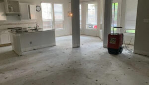 A large room with a kitchen island, concrete floor, and a red dehumidifier for water