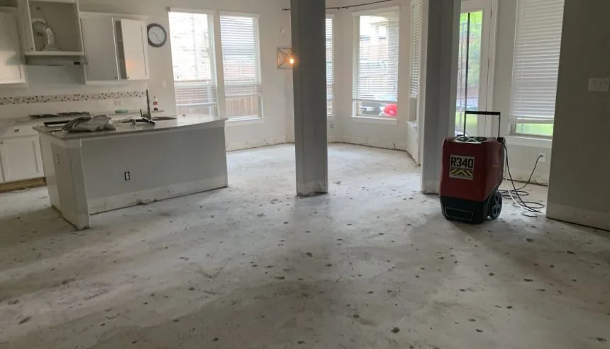 A large room with a kitchen island, concrete floor, and a red dehumidifier for water