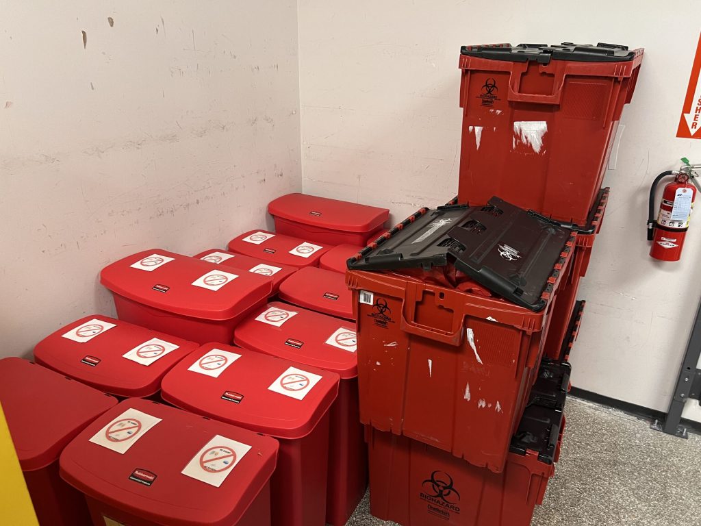 Technician labeling a sealed biohazard waste container
