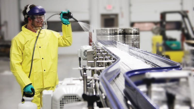 Technician in full PPE disinfecting surfaces in a commercial space