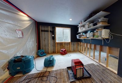 Interior of a residential home with water extraction equipment operating across multiple rooms, showing hoses, vacuums, and floor drying mats