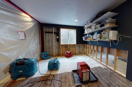 Interior of a residential home with water extraction equipment operating across multiple rooms, showing hoses, vacuums, and floor drying mats