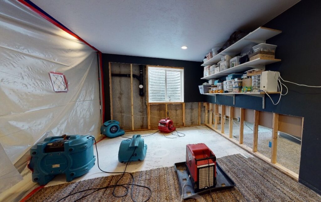 Interior of a residential home with water extraction equipment operating across multiple rooms, showing hoses, vacuums, and floor drying mats