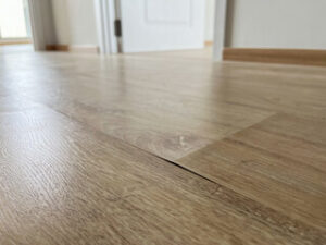 Bubbling laminate floor with a visible gap, showcasing the issue in a home setting.