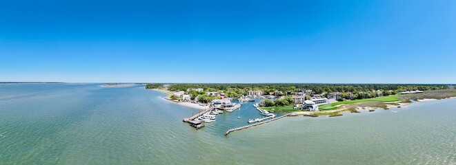 Sunny aerial panorama of a coastal resort town featuring a marina, beach, and golf course