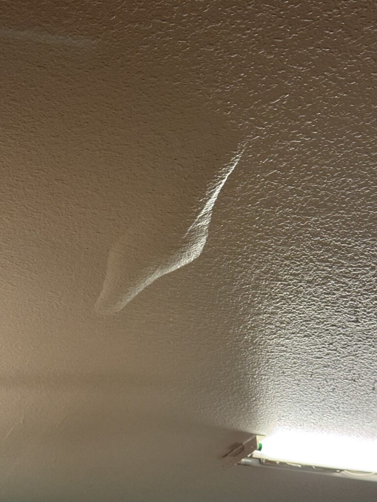 Ceiling bulge showing hidden signs of water damage, bubbling paint, and musty odors in a Lowcountry home — early indicators of moisture behind walls.