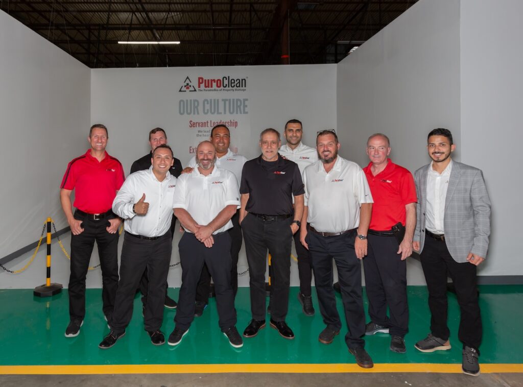 PuroClean Commercial Sales Class attendees posing in front of a company backdrop.
