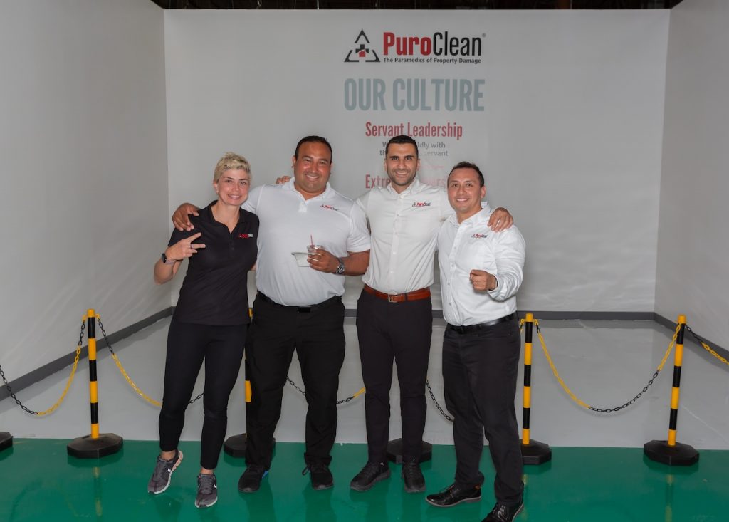 John Villon and Nilo Quiroz pose in front of a PuroClean backdrop for the Commercial Sales Class 2.0 after-party.