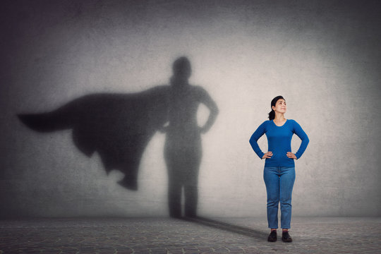 Woman standing with superhero shadow. representing the community and making an impact on those around her.