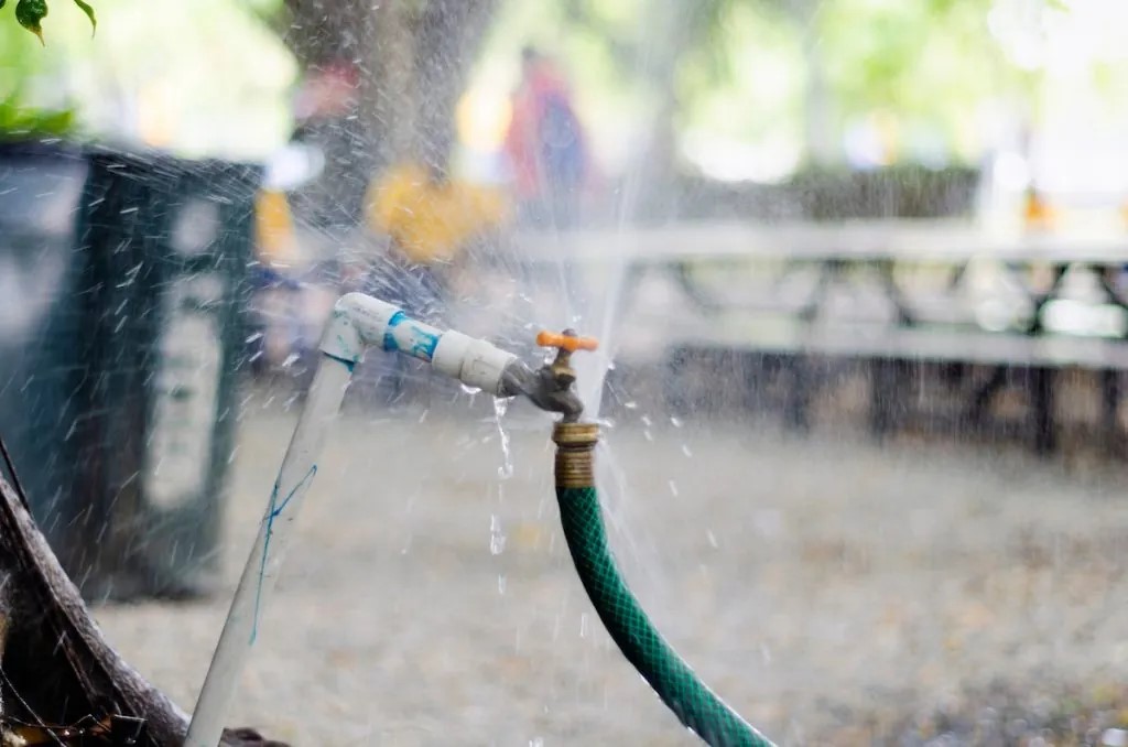 a hose leaking near a home. an outdoor leak can cause an indoor leak