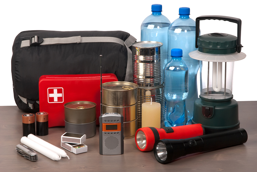 Hurricane preparedness kit with water, non-perishable food, flashlights, batteries, and first aid supplies ready for emergency use.