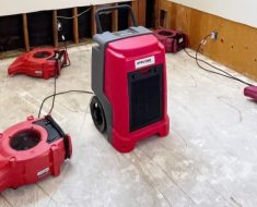 Dehumidifier and air movers operating on a concrete floor during water damage restoration
