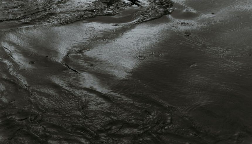 Dark, contaminated floodwater with ripples and raindrops, illustrating the hazardous and unpredictable nature of black water. category 3