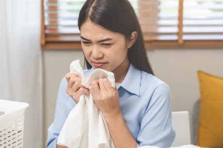 woman smelling musty clothes after water damage in her home