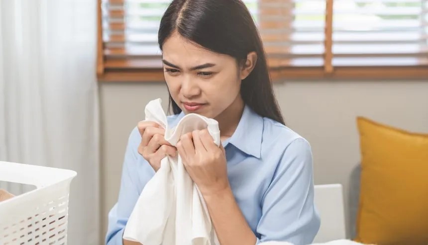 woman smelling musty clothes after water damage in her home