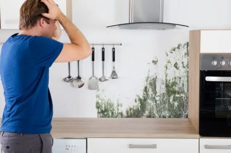 man standing in kitchen with mold on the walls