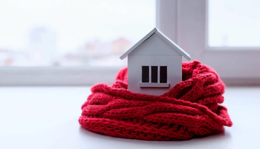 Miniature house wrapped in a red scarf symbolizing winter home protection on Long Island.