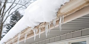 Icicles along a snow-covered gutter, an early warning of ice dam water damage