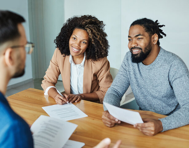 A couple speaking to an insurance agent about claim savings.
