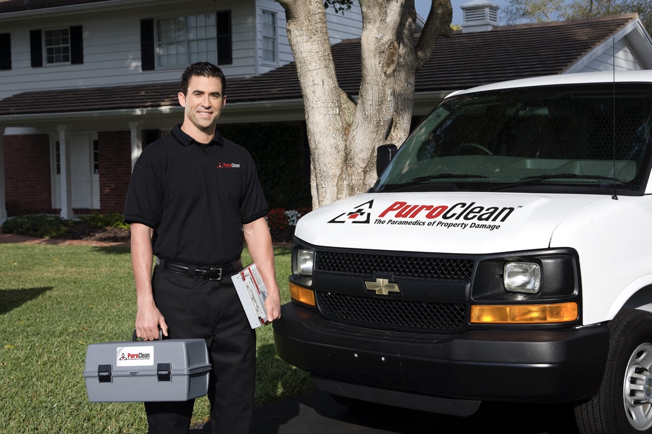 PuroClean technician in front of PuroClean vehicle at residential property.