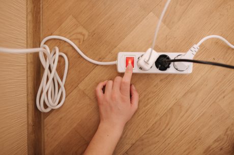 Overhead view of a hand turning on a white power strip