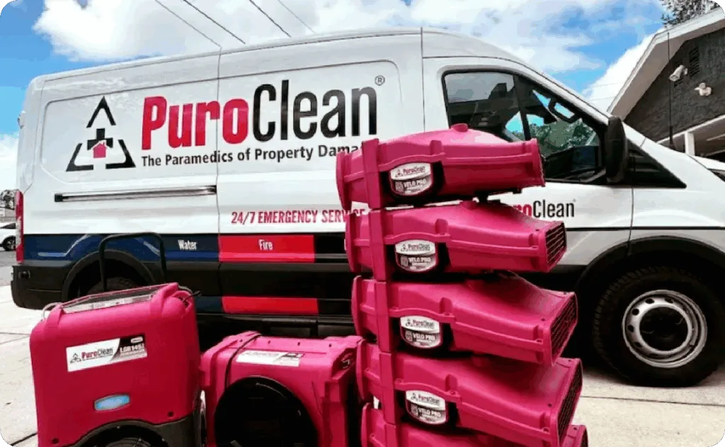 A PuroClean emergency service van is parked with several pink drying and restoration machines. TITLE: