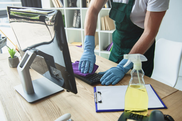 person wearing rubber gloves cleaning keyboard at the office