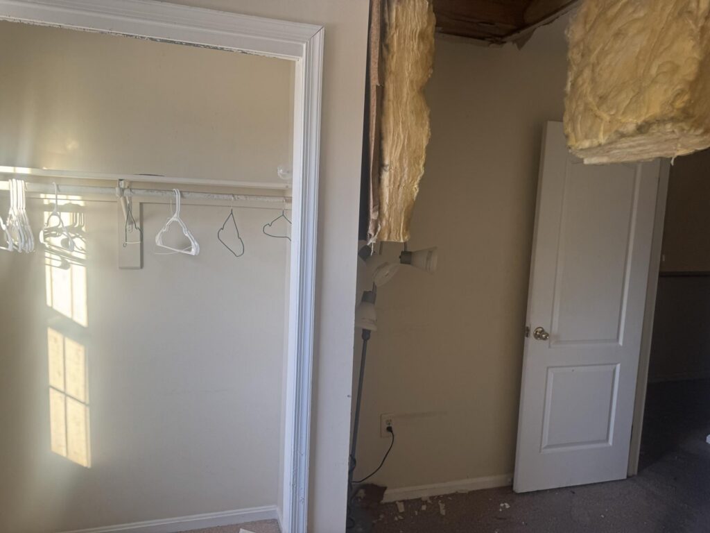 An interior room undergoing renovation with an empty closet and exposed wall insulation. TITLE