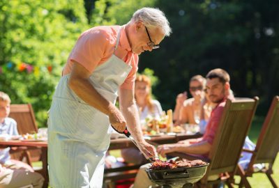 senior man cooking meat on barbecue grill outdoors
